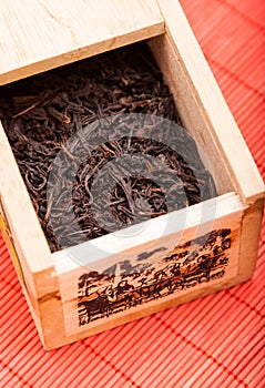 Box with black tea on red mat