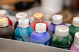 Box with bottles of acrylic paints of different colors. The bottles are dusty because they have not been used for a long time