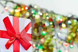 Box with christmas gift with red bow and christmas bokeh light abstract holiday background