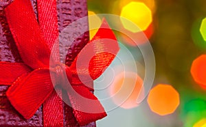 Box with christmas gift with red bow and christmas bokeh light abstract holiday background.