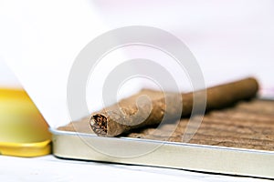 Box of cigarillos on a white background. On the box is one cigarillo