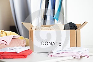 Box with clothes for charity and recycling at home on the table