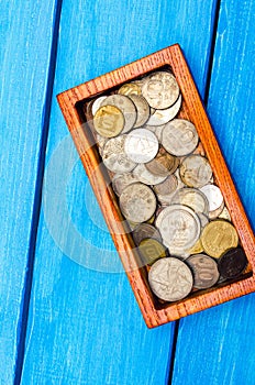 box with coins of countries of the world on a blue wooden background. money.a Palestinian coin, a Soviet coin, an Israeli