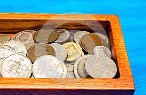 box with coins of countries of the world on a blue wooden background. money. a Palestinian, a Soviet, an Israeli, a Ukrainian coin