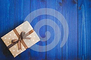 Box in craft paper, eco paper on the wooden table. Top view. Brown paper wrapped gift box with satin ribbon bow on a old rustic wo