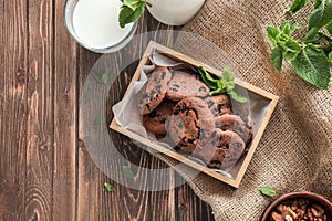 Box with delicious chocolate cookies and glass of milk on wooden background