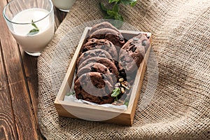 Box with delicious chocolate cookies and glass of milk on wooden table