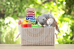 Box with different child toys on table