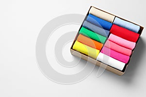 Box with different colorful socks on light background, above view. Space for text
