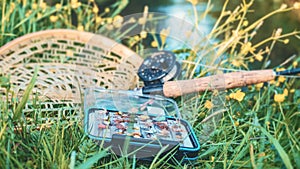 Box with flies, nets and a fly fishing rod. Fishing gear