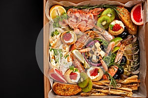 A box of food, cheese, breads, fish, shrimp. Food delivery for the company, romantic, office dinner at home. Beautiful composition