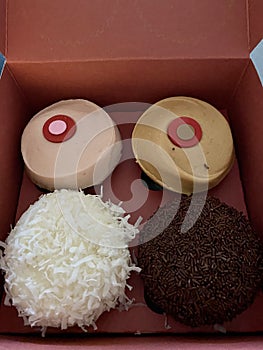 Box of four cupcakes coconut chocolate strawberry caramel