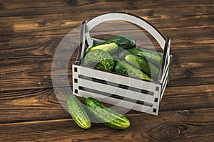 A box of fresh cucumbers on a brown wooden table