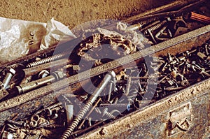 Box full of old screws and nuts in different conditions.