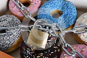 Box full of tempting delicious donuts wrapped in metal chain and lock in sugar and sweet addiction photo