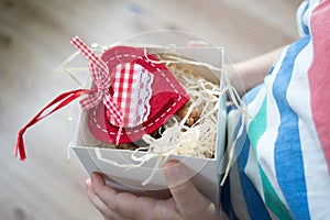 Box with a gift valentine heart in a child& x27;s hand on Valentine& x27;s