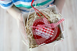 Box with a gift valentine heart in a child& x27;s hand on Valentine& x27;s