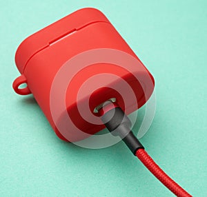 Box with a headphone charger in a red case attached to the cable on a green background