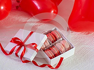 Box with macaron cookies and red baloons on the bed