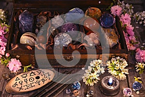 Box with magic crystals and stones, black candle and spring flowers