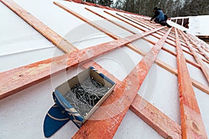 The box with nails on the roof and roofer working on roof structure of building on construction site