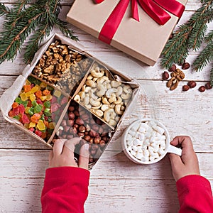 A box of nuts and dried fruits on old wooden background. hazelnut, cashew, dried daddy, dried pineapple. Gift box with bow