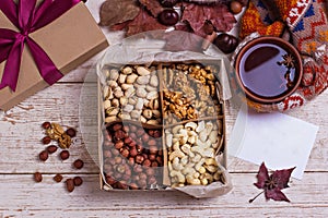 A box of nuts and dried fruits on old wooden background. hazelnut, cashew, dried daddy, dried pineapple. A gift on the day of the