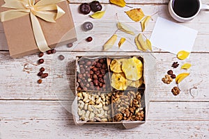 A box of nuts and dried fruits on old wooden background. hazelnut, cashew, dried daddy, dried pineapple. A gift on the day of the