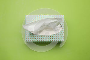 Box of paper tissues on light green background, top view