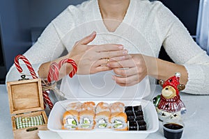 A box of Philadelphia rolls on the table in the kitchen. Fast delivery sushi in a white container