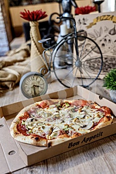 Box of pizza next to a monocycle inside a room