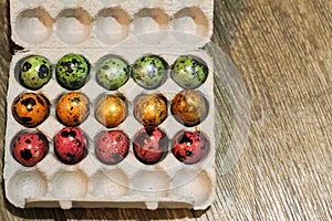 Box with the quail eggs painted different colors. holiday Easter. top view. wooden background