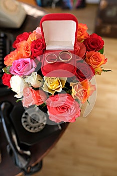 Box with red box with jewelry lies on a bouquet of colored roses, concept of holiday, anniversary of married couple, valentine`s