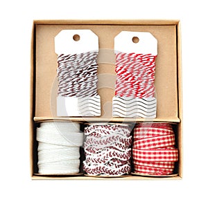 Box with ribbons and threads for scrapbooking on white background