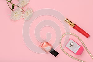 Box with ring and women cosmetics on a pink background