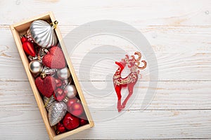 Box with silver red christmas gifts on white wooden background
