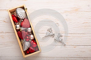 Box with silver red christmas gifts on white wooden background