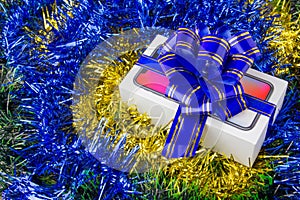 A box with a smartphone inside. Festively packed box with a popular smartphone inside on Christmas decorations.