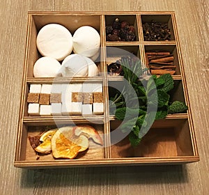 Box for spices on a wooden table, additives for tea