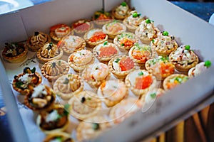 A box of tartlets stuffed with salads and seafood. Catering.