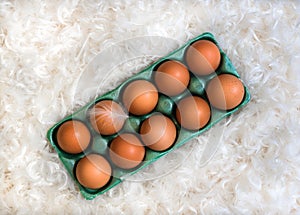 Box with ten brown eggs in the pile of white