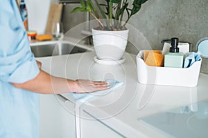 Box with things for cleaning kitchen on background of young woman at home