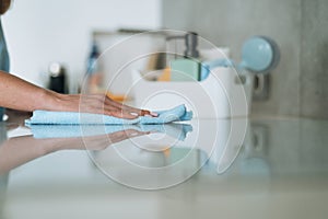 Box with things for cleaning kitchen on background of young woman at home