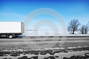 Box truck on the winter road against blue sky