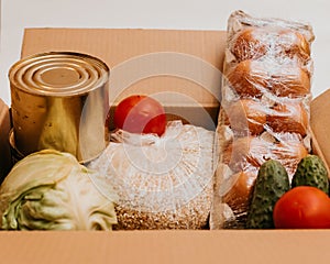 Box whith cucumbers,cereals, bananas, oranges, cabbage, tomatoes, vegetable oil,cabbage, eggs and canned goods isolated on white