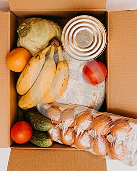 Box whith cucumbers,cereals, bananas, oranges, cabbage, tomatoes, vegetable oil,cabbage, eggs and canned goods isolated on white