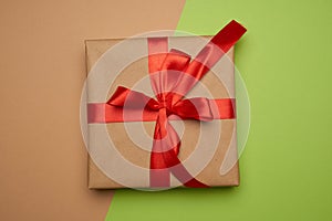 Box wrapped in brown paper and tied with a silk red ribbon with a bow