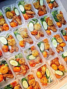 boxed rice with a variety of side dishes, namely chicken wings, eggs  and vegetables for going to work or on vacation