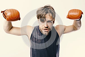 Boxer demonstrates his strong muscles. Man with bristle and impudent face wears boxing gloves. Athlete with leather box