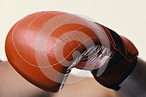 Boxer demonstrates red leather glove in close up. Athlete with box equipment isolated on white background